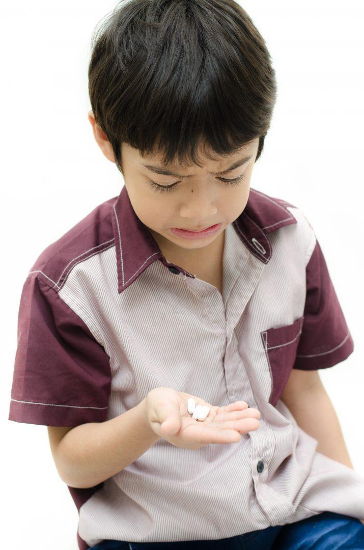Little boy does'n want to take medicine pill on white background